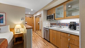 A hotel room with a bed, bedside table with a lamp, a small kitchenette with a microwave, coffee maker, and a dishwasher. - 334 | Mtn Loft Escape w/ A/C - Fridge, Tubs & Gym (Olympic Valley)