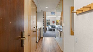 A hallway with wooden doors, a grey sofa, and a view of the outside. - 314 | Loft Escape - King Bed, Views, Hike & Bike (Olympic Valley)