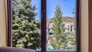 A room with a large window offering a view of a residential area with houses and trees.