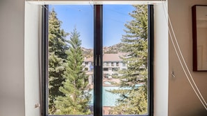 A window with a view of a house, trees, and a swimming pool. - 305 | Pool View A/C Loft!  - Tubs, Sauna & Fun (Olympic Valley)