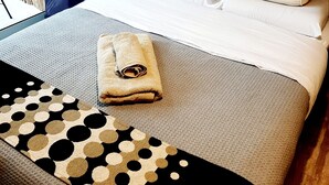 A neatly made bed with white linens and two pillows, a rolled-up towel, and a patterned throw on a textured bedspread. - Apartment in Palermo Hollywood, Buenos Aires, Argentina (Buenos Aires)