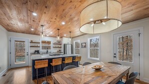 Una cocina amplia con una isla grande de madera, taburetes de bar y una mesa de comedor con sillas.