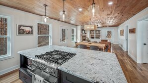 Una cocina amplia con una isla grande, techo de madera e iluminación colgante.