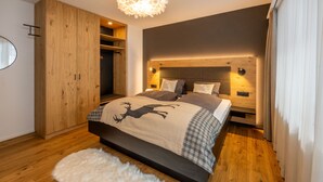 Een moderne slaapkamer met een groot bed, een houten garderobe en een zacht vloerkleed.