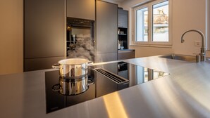 Een moderne keuken met een ingebouwde kookplaat, een pan op het aanrecht en een raam met uitzicht op een balkon.