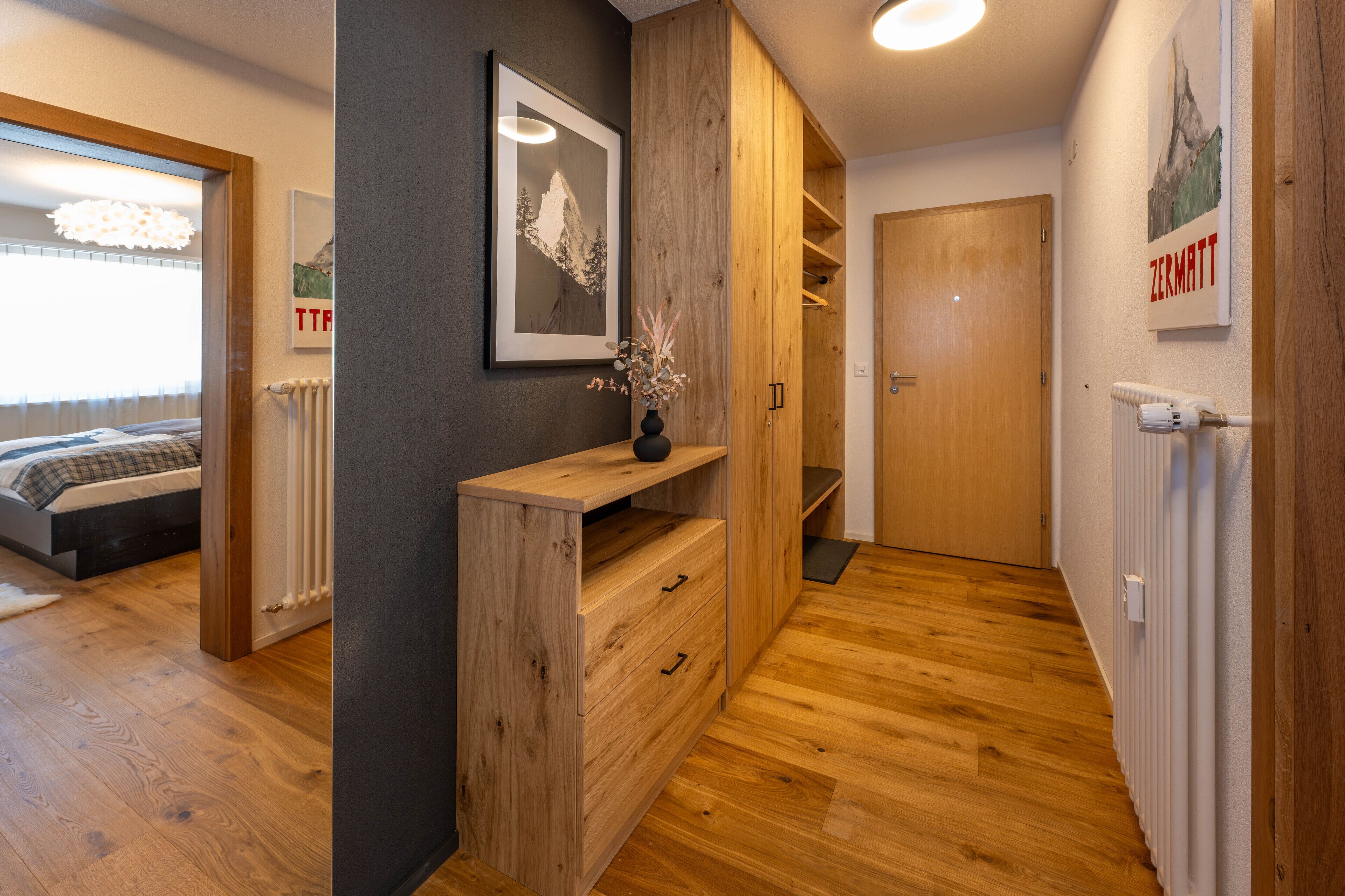 Quarto moderno com piso de madeira, cama, cômoda e um quadro na parede.