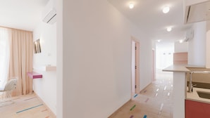 Une chambre d’hôtel moderne dotée d’une grande fenêtre, d’un fauteuil, d’une petite table et d’un coin cuisine.