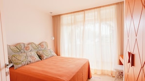 Une chambre à coucher avec un lit, des rideaux et un mur orné de motifs géométriques.