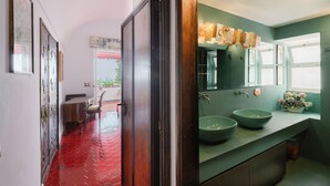 Une salle de bain avec un mur recouvert de carreaux verts, deux lavabos et une fenêtre.