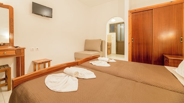 A hotel room with a large bed, a wooden desk, a television, and a wardrobe. - Mariliki Studios (Zakynthos)
