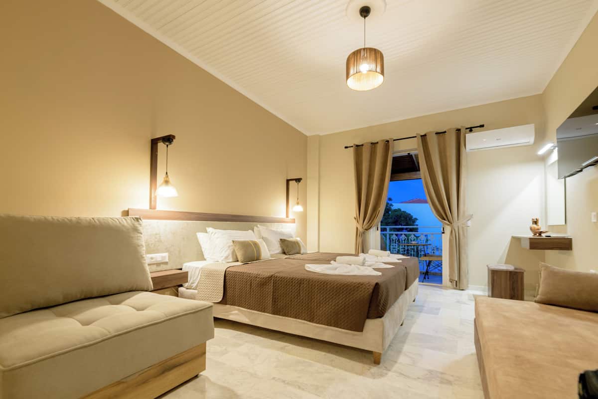 A modern hotel room with a large bed, a sofa, and a balcony with curtains.