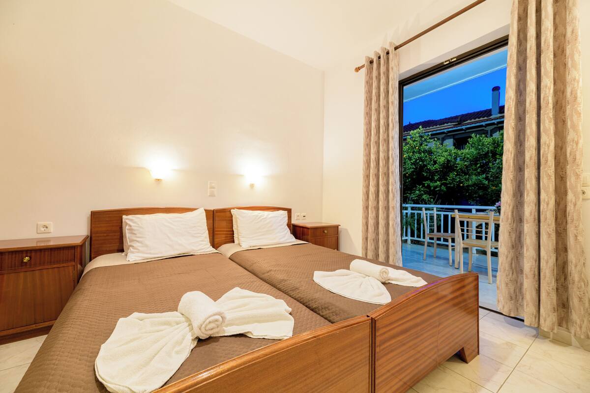 A double bed with two pillows, a wooden nightstand, and a bathroom mirror.