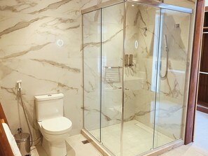 Une salle de bain avec une douche en verre, des toilettes et des murs en marbre.