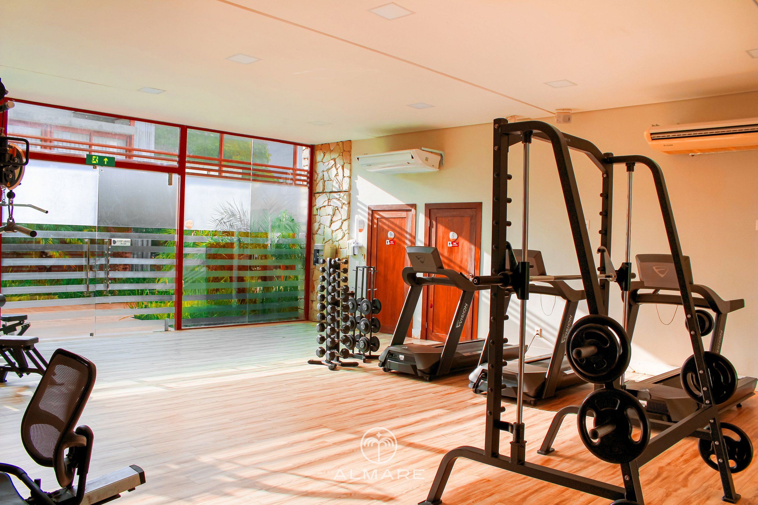 Un gimnasio con cintas de correr, máquinas de pesas y una variedad de mancuernas.