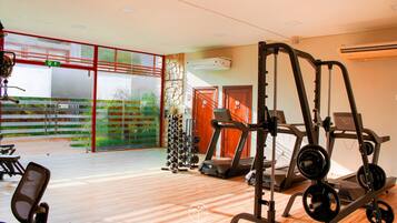 Un gimnasio con cintas de correr, máquinas de pesas y una variedad de mancuernas.