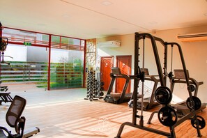 Een sportschool met loopbanden, krachttoestellen en diverse gewichten.