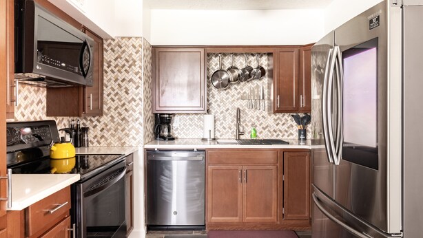 Una cocina compacta con armarios de madera, electrodomésticos de acero inoxidable, un microondas y un lavavajillas.