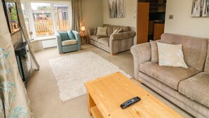 Un salon avec un canapé, un fauteuil, une table basse et un téléviseur.