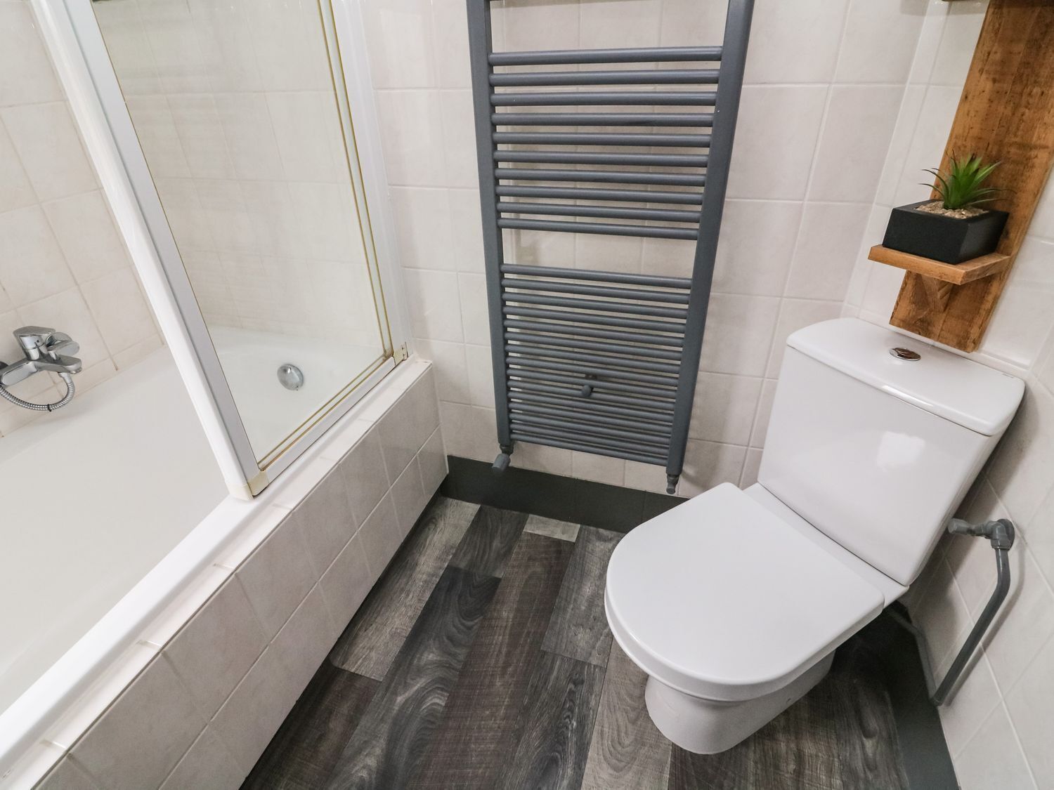 A bathroom with a shower, toilet, and a towel rack.