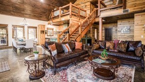Ein großzügiger Wohnbereich mit einer Holztreppe, Ledersofas und einem großen Teppich.