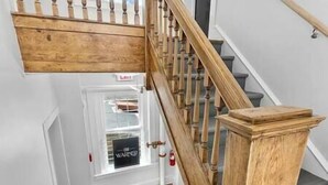 A wooden staircase with a handrail and a door with a 'Fire Alarm' sign. - Modern Downtown 1BR | Free Garage Parking + Workspace (Wilmington)