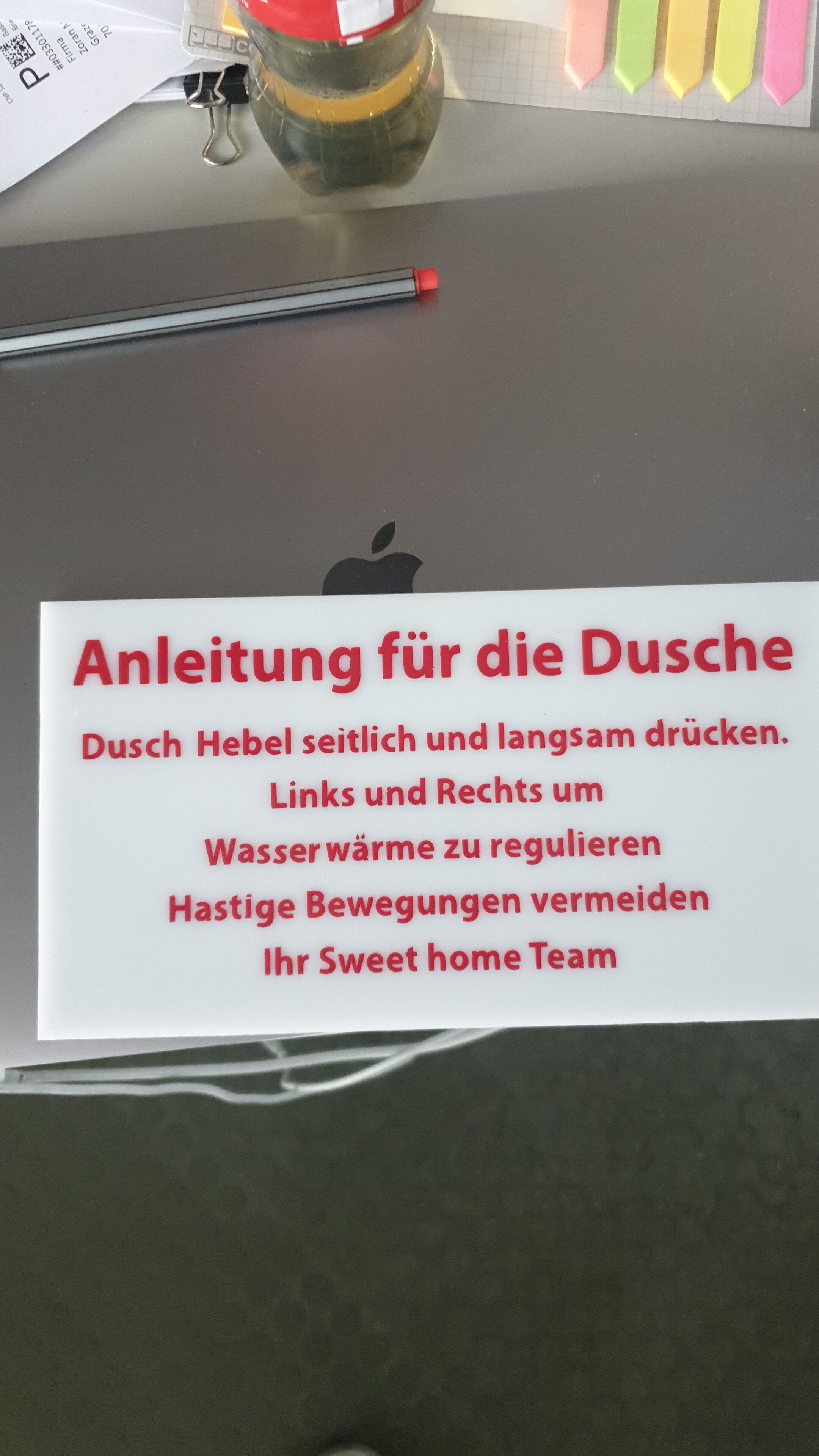 A white sign with red text in German, placed on a table.