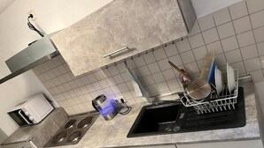 Uma cozinha equipada com fogão, forno e lava-louças. Há um escorredor de louça com pratos e uma panela na bancada.