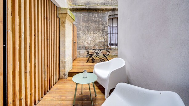 Un étroit couloir en bois, avec une petite table et deux chaises blanches.