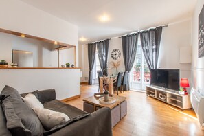 Ein modernes Wohnzimmer mit Sofa, Couchtisch, Fernseher und Essbereich.