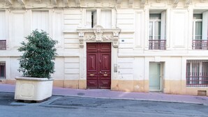 A building with a large, ornate entrance door, a potted plant, and a balcony with metal railings.