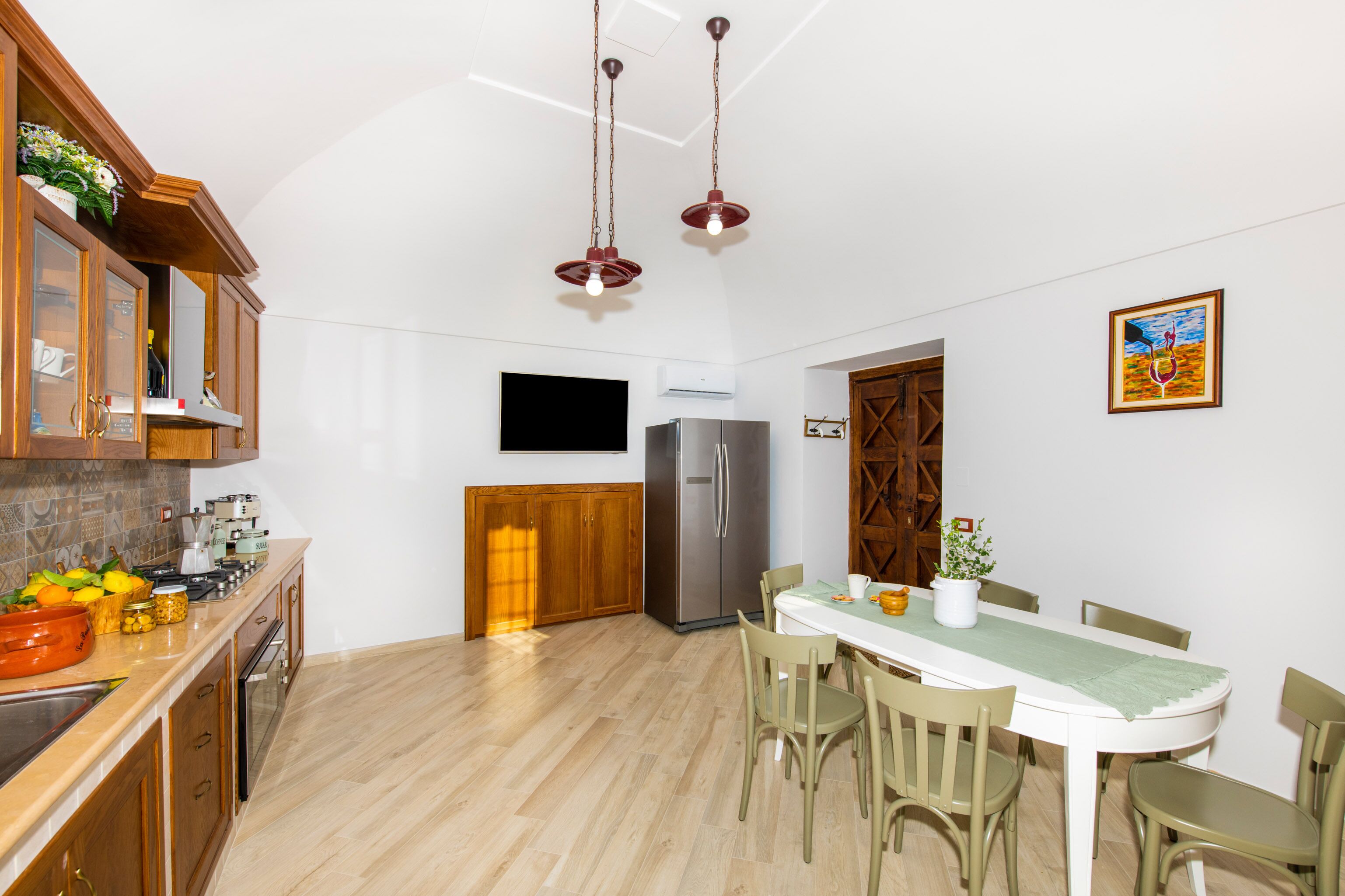 Una cucina moderna con mobili in legno, un frigorifero in acciaio inossidabile e un'area pranzo con tavolo e sedie.