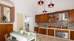 Eine moderne Küche mit Holzschränken, einem Einbauofen und einem Essbereich mit Tisch und Stühlen.