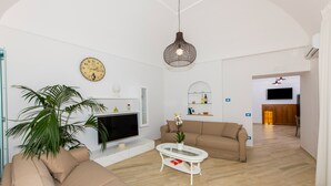 Ein Wohnzimmer mit Sofa, Fernseher, Couchtisch und einer Pendelleuchte.