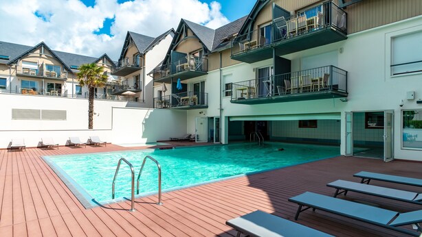 Ein Poolbereich auf dem Dach mit Holzterrasse, Liegestühlen und einem klaren, blauen Pool.