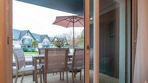 Eine Terrasse mit Tisch und Stühlen, einem Sonnenschirm und Blick auf Häuser im Hintergrund.
