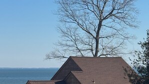 A two-story house with a brown roof and a view of the sea.