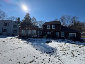 Een huis met twee verdiepingen, een grote voortuin vol sneeuw, een garage en een oprit.