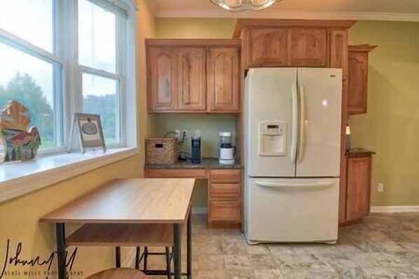 Una cocina con armarios de madera, un refrigerador blanco, una cafetera y una ventana con vistas.