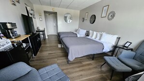 A hotel room with a bed, two armchairs, a coffee station, and a desk. - Lake View Cedar Lodge Room w/ Private Balcony (Laconia)
