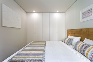 Un dormitorio con cama, almohadas, cabecero, una obra de arte en la pared y un armario.