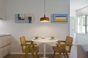 Ein Essbereich mit einem runden Tisch, vier Holzsesseln, einer hängenden Pendelleuchte und zwei an der Wand befestigten abstrakten Gemälden.