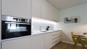Una cocina moderna con armarios blancos, un horno Bosch, un lavamanos y una silla de madera.