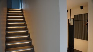 A modern staircase with illuminated steps leading to a dark room. - Ferienhaus in Lüneburg (Westergellersen)