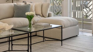 A modern living room with a white sofa, a glass coffee table, and a view of a balcony with a white railing. - "62 Blue View" Lakefront Private Pool Short Walk to the Beach (Santa Rosa Beach)