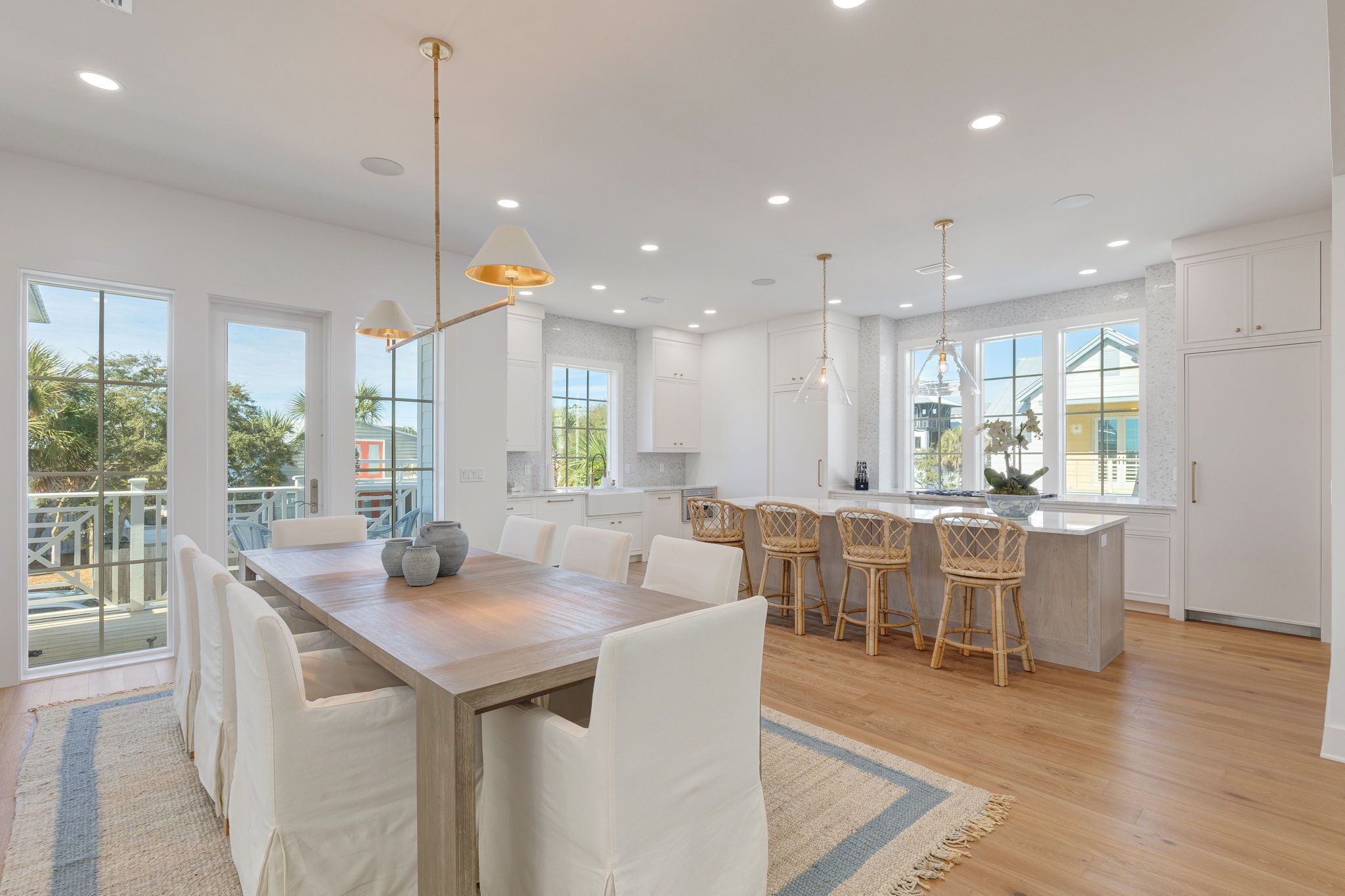 A modern kitchen with white cabinetry, a wooden island, and a dining area with white chairs.