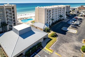 A hotel with a swimming pool, a parking lot, and a view of the beach. - Beach House 604C - Gulf Front Resort! (Miramar Beach)