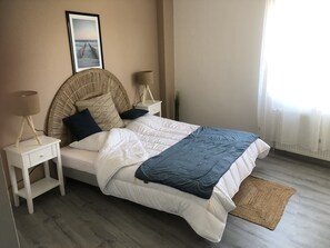 Quarto bem arrumado com uma cama, duas mesas de cabeceira, uma luminária de parede e um quadro emoldurado.