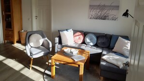 A living room with a grey sofa, a wooden coffee table, and a grey armchair. - Liebevoll Saniertes Ferienhaus in Ruhiger Warftlage in Dagebüll-kirche (Dagebüll-Kirche)