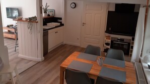 A compact living space with a dining area, kitchenette, and a TV. - Liebevoll Saniertes Ferienhaus in Ruhiger Warftlage in Dagebüll-kirche (Dagebüll-Kirche)