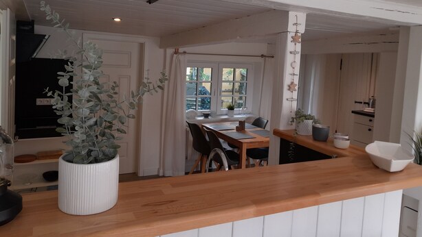 A kitchen with a wooden countertop, a dining area with a table and chairs, and a potted plant. - Liebevoll Saniertes Ferienhaus in Ruhiger Warftlage in Dagebüll-kirche (Dagebüll-Kirche)